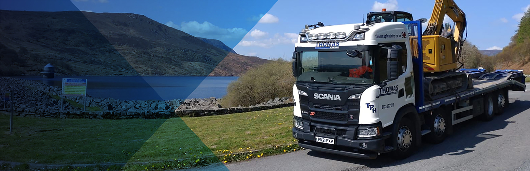 Thomas Plant Hire low-loader transporting an excavator beside a Welsh reservoir